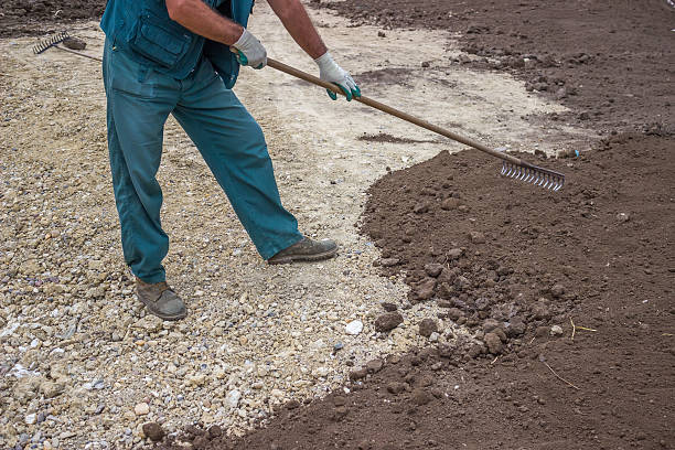 Raking soil to create a flat surface for paver installation