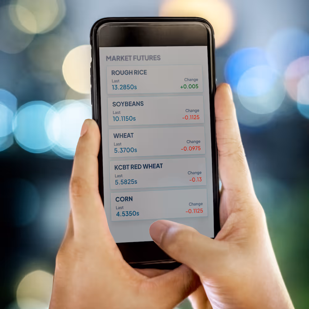 hands holding a cell phone displaying a market futures stock ticker.
