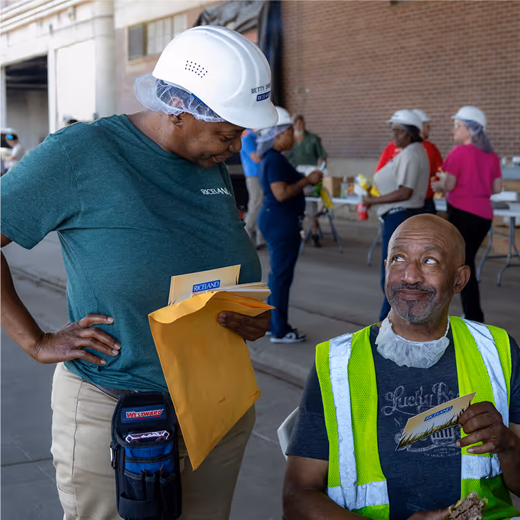 Two Riceland employees sharing a friendly moment during an outdoor workplace event.