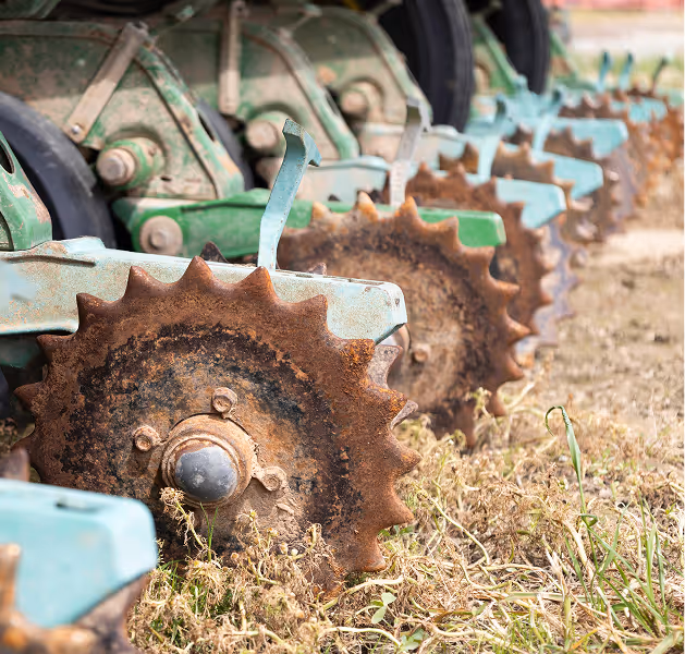 Close-up of metal discs on agricultural equipment lined up in a field.