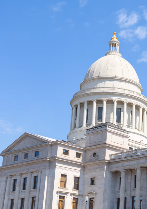 White stone government building with a dome and blue sky.