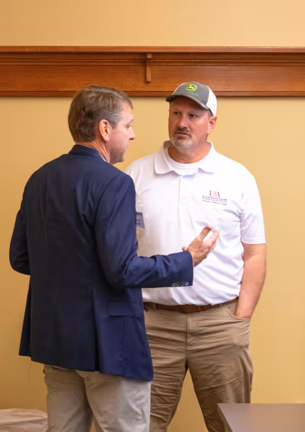 Two men having a discussion during an agricultural meeting.