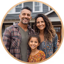 Smiling family of three standing outdoors with a house in the background.