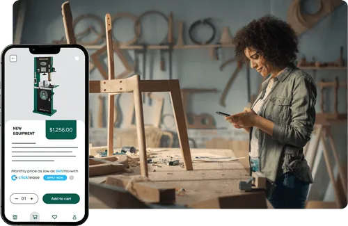 Woman looking at her phone while standing beside her workbench with half assembled chair