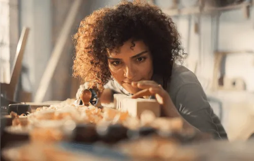 Woman examining a piece of wood she has been woodworking