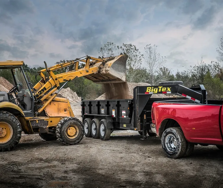 A man using a construction loader dumping dirt into a trailer
