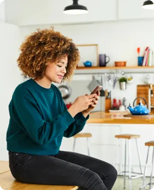 a woman sitting on a stool looking at her cell phone
