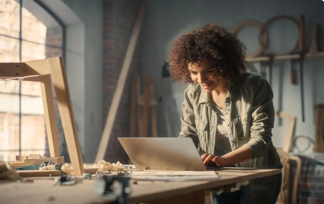 a woman working on a laptop in a workshop