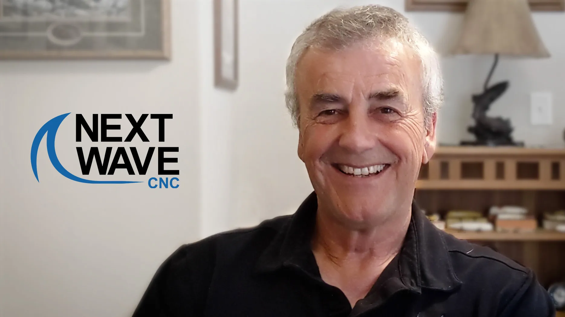 a smiling man in a black shirt in a room