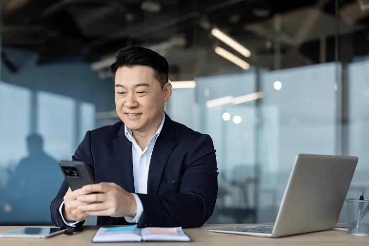 A man in a suit is looking at his cell phone. - ASCII Group Images