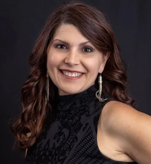 A woman wearing a black dress and earrings smiles for the camera. - ASCII Group Images