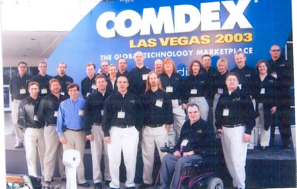 A group of people standing in front of a sign for Comdex Las Vegas 2000. - ASCII Group Images