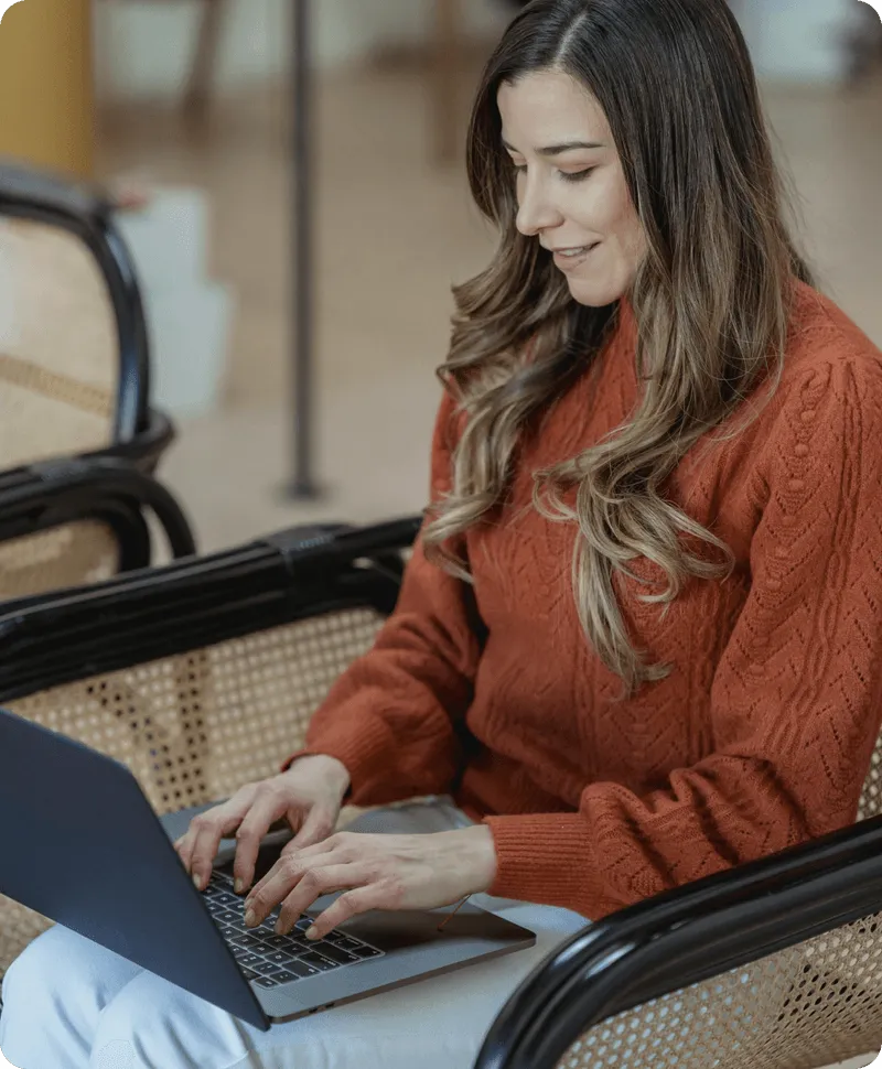 A girl studying on her computer while taking notes on a book