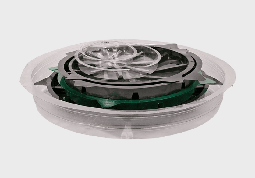 Translucent plastic container with stacked green and black circular inserts inside.