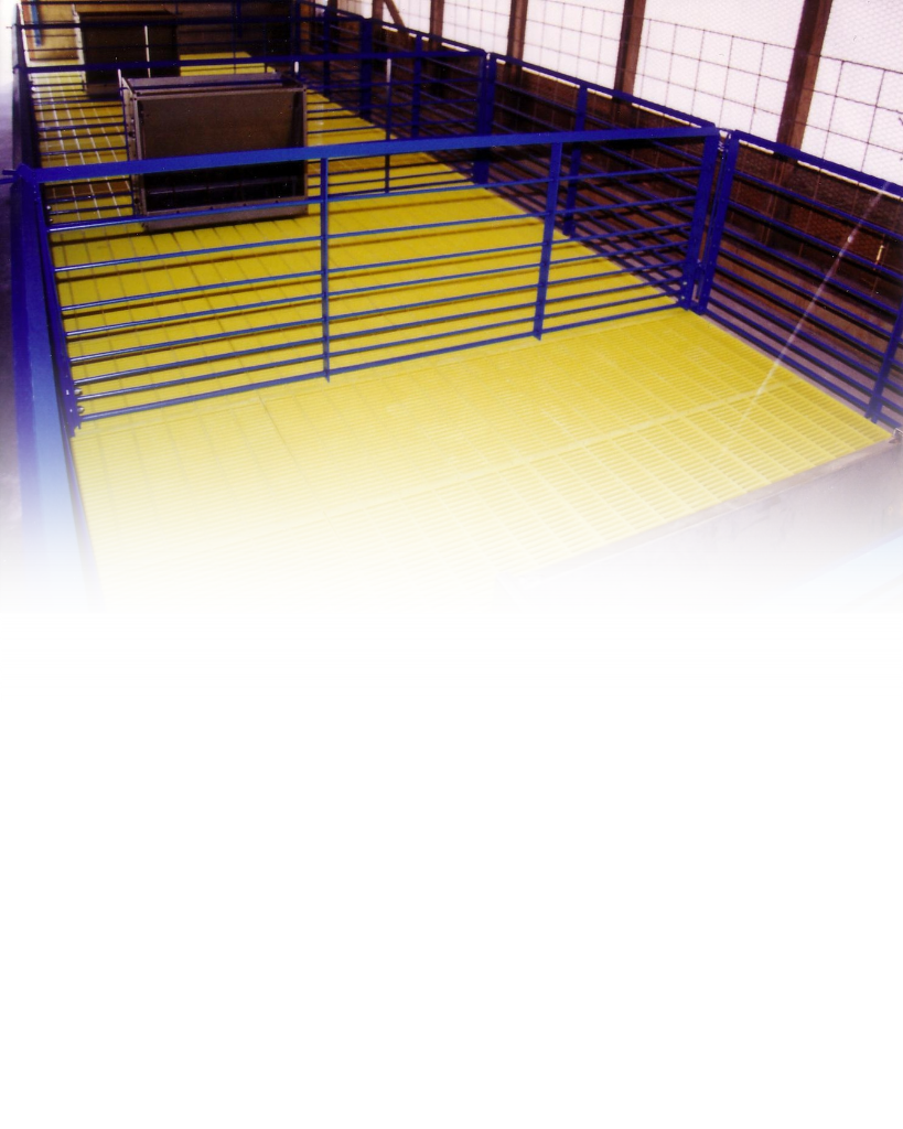 Indoor animal pen with blue metal railings and yellow grated flooring inside a building.