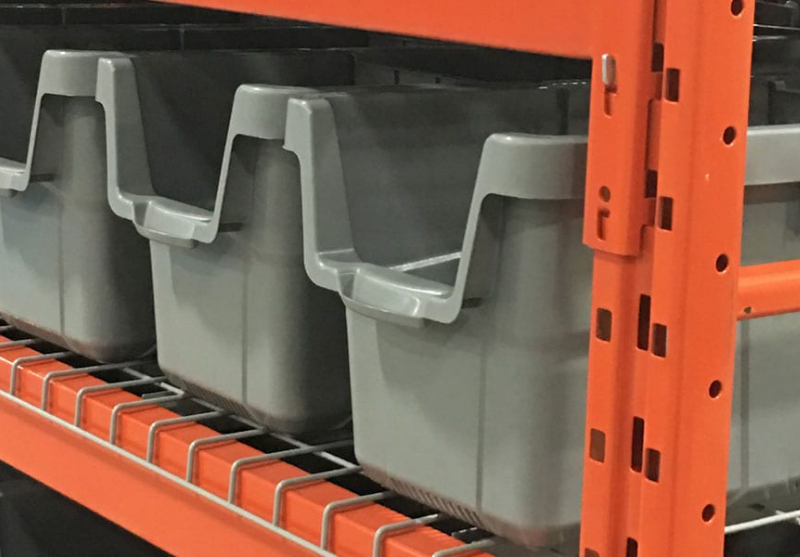 Gray plastic storage bins placed on an orange metal industrial shelving unit.