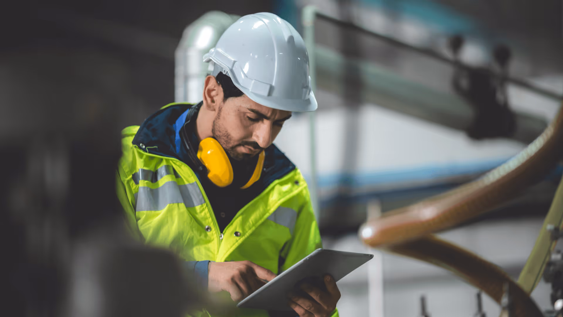 A man wearing a white safety helmet and a yellow high-visibility jacket with reflective stripes.