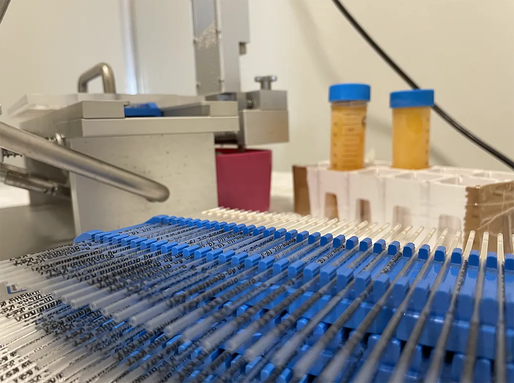 Rows of insulin syringes with blue caps lined up on a blue rack in a clinical setting.