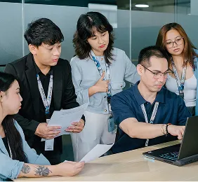 A group of people standing around a laptop computer.