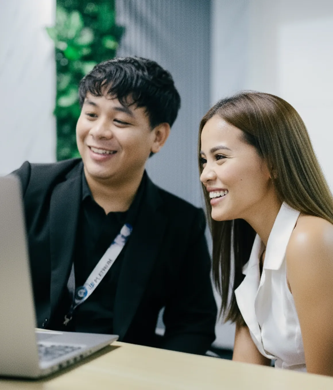 A man and a woman sitting in front of a laptop computer.