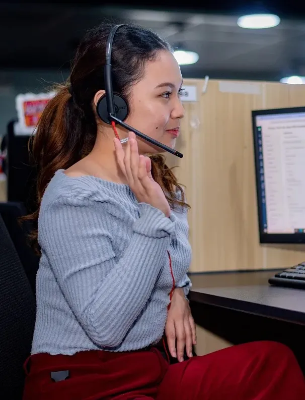 A woman sitting in front of a computer wearing a headset.