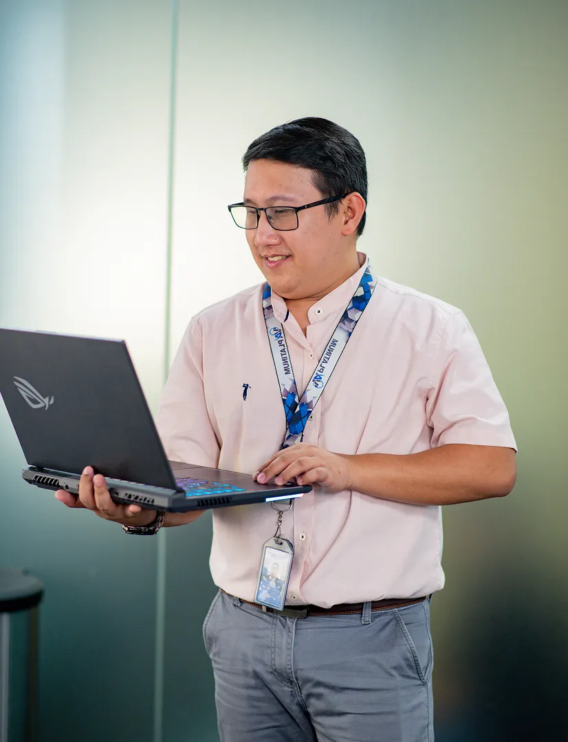 A man in a pink shirt is using a laptop.
