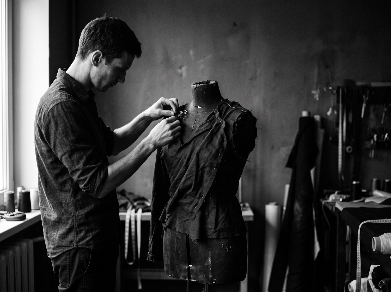 Dress form and unfinished garment in a dark studio