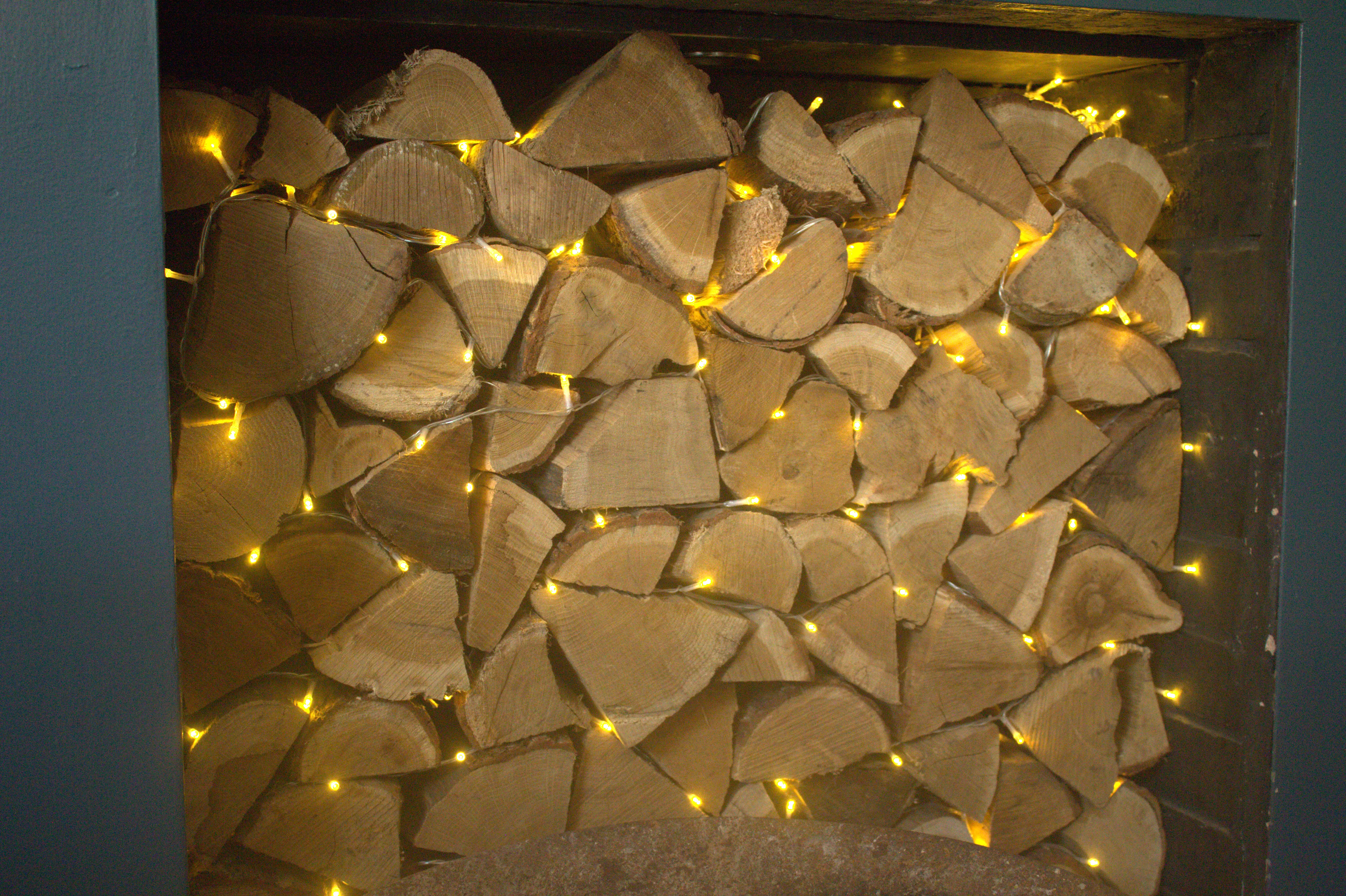 cosy fairy lights and chopped wood in a pub fireplace. 