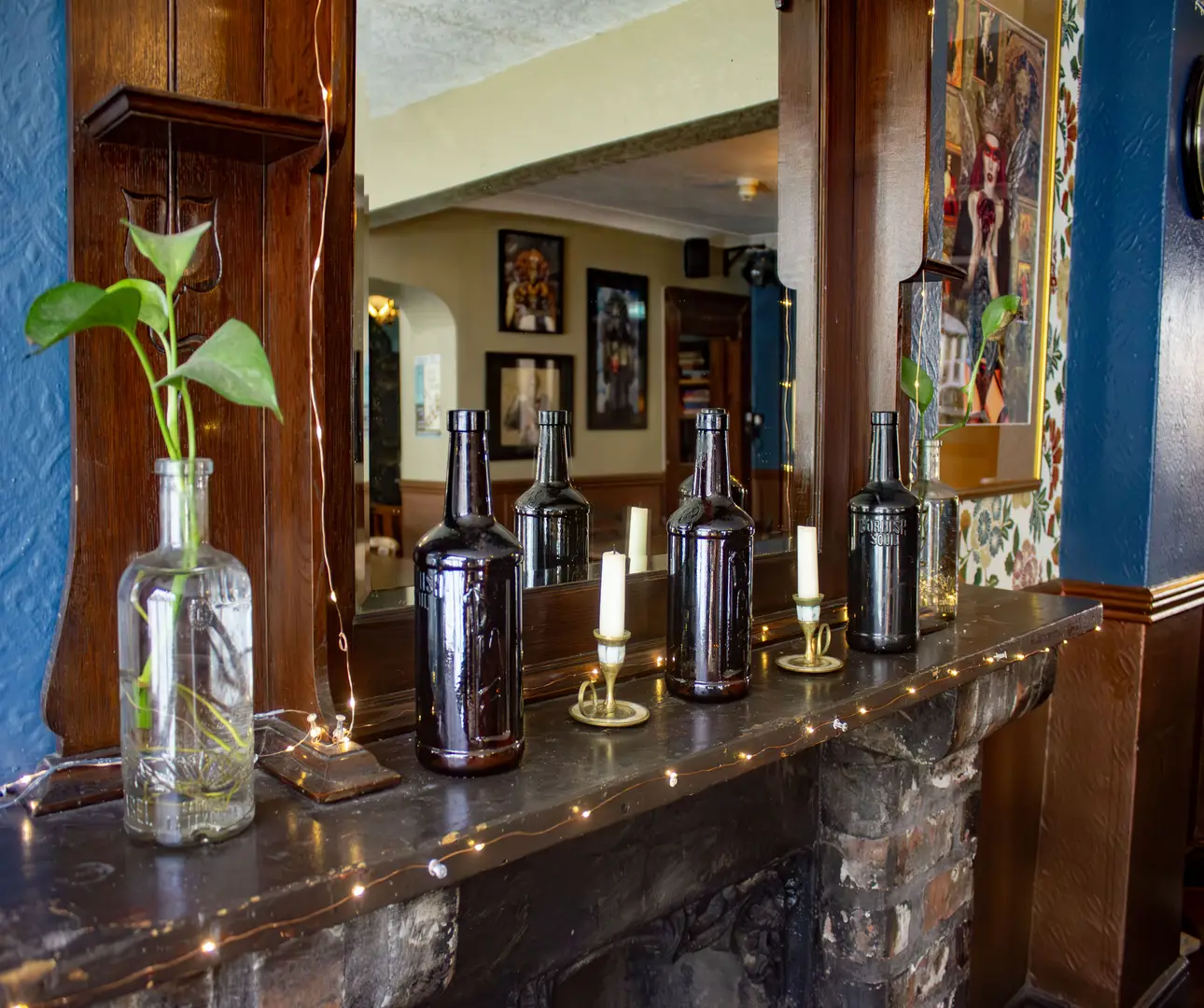 Decorative bottles, plants and fairy lights in a pub, homely, cosy vibes with artwork from local artists featured. 
