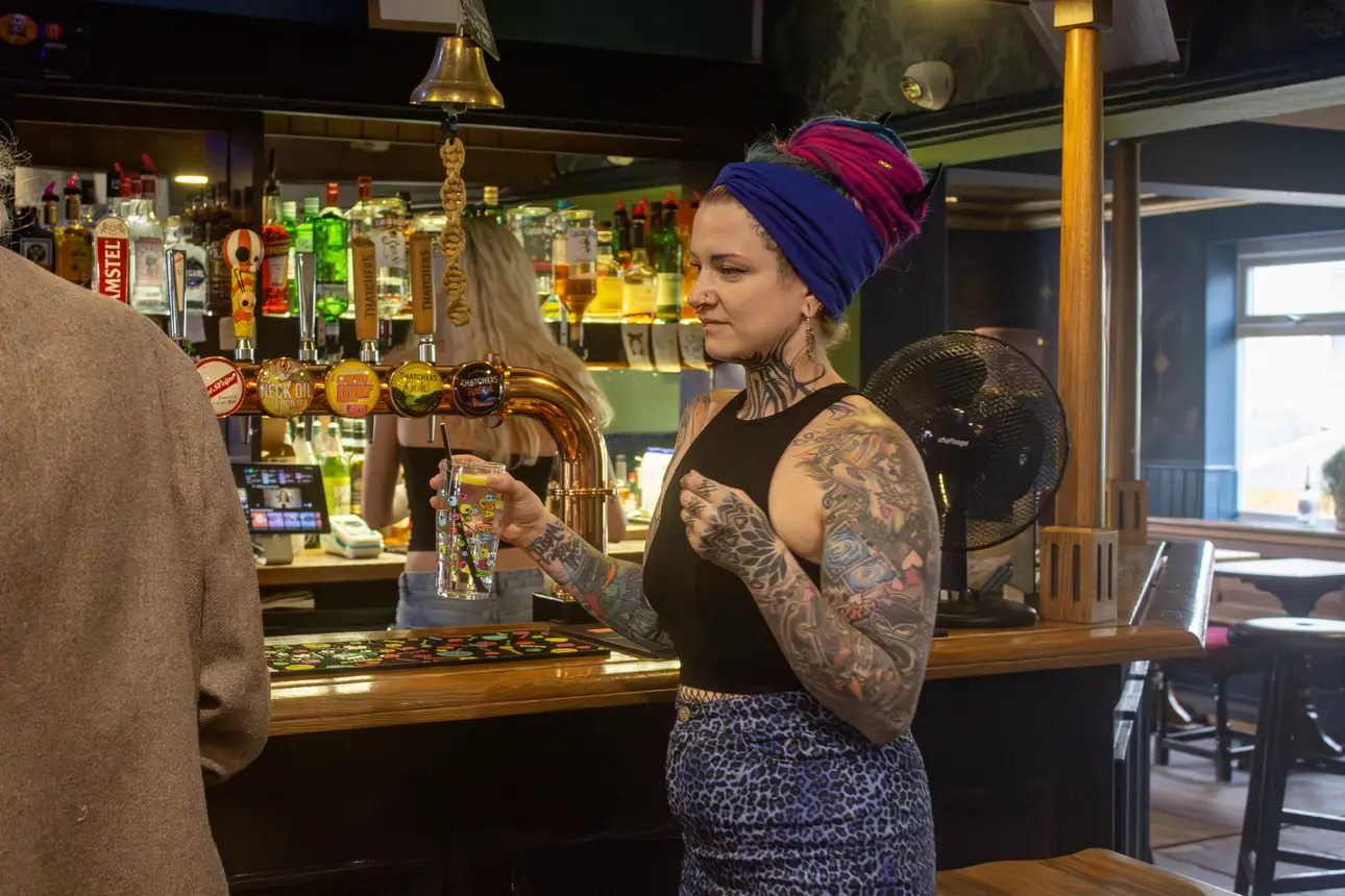 Local customer carrying her drink from the bar. Wide range of drinks from an alternative welcoming pub in Totterdown.  
