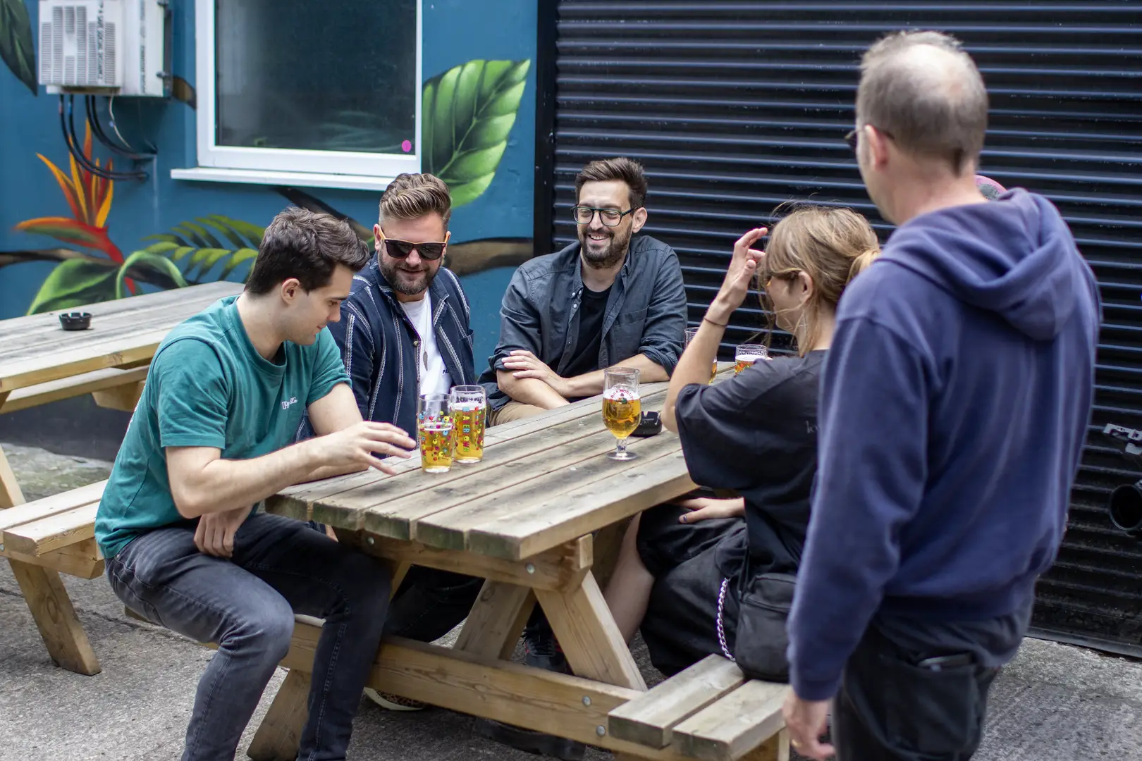 Customers laughing in a colourful pub garden and drinking 