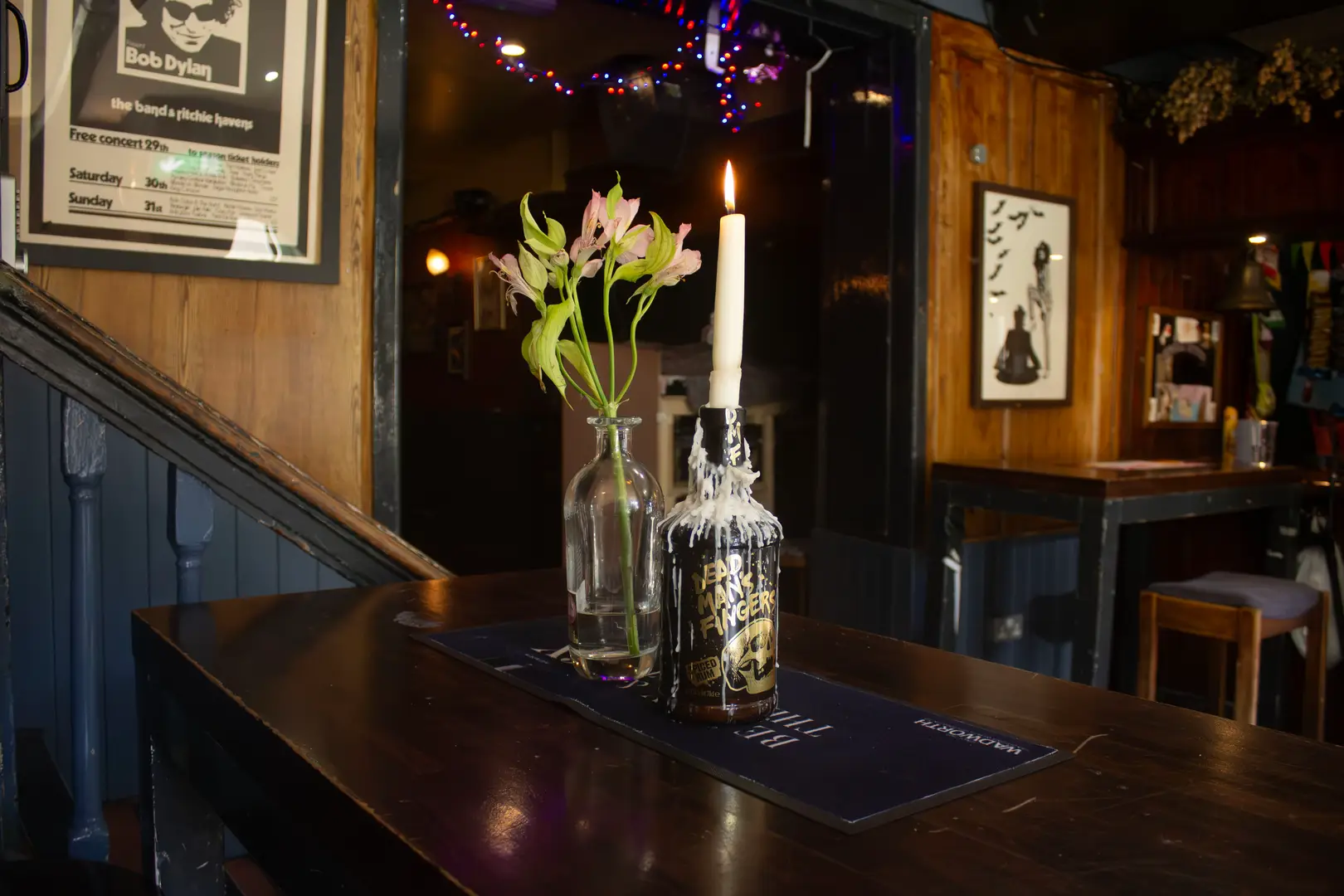 A cosy, inviting table adorned with flowers and a dripping candle, in a historic pub full of charm, history, and a friendly atmosphere.