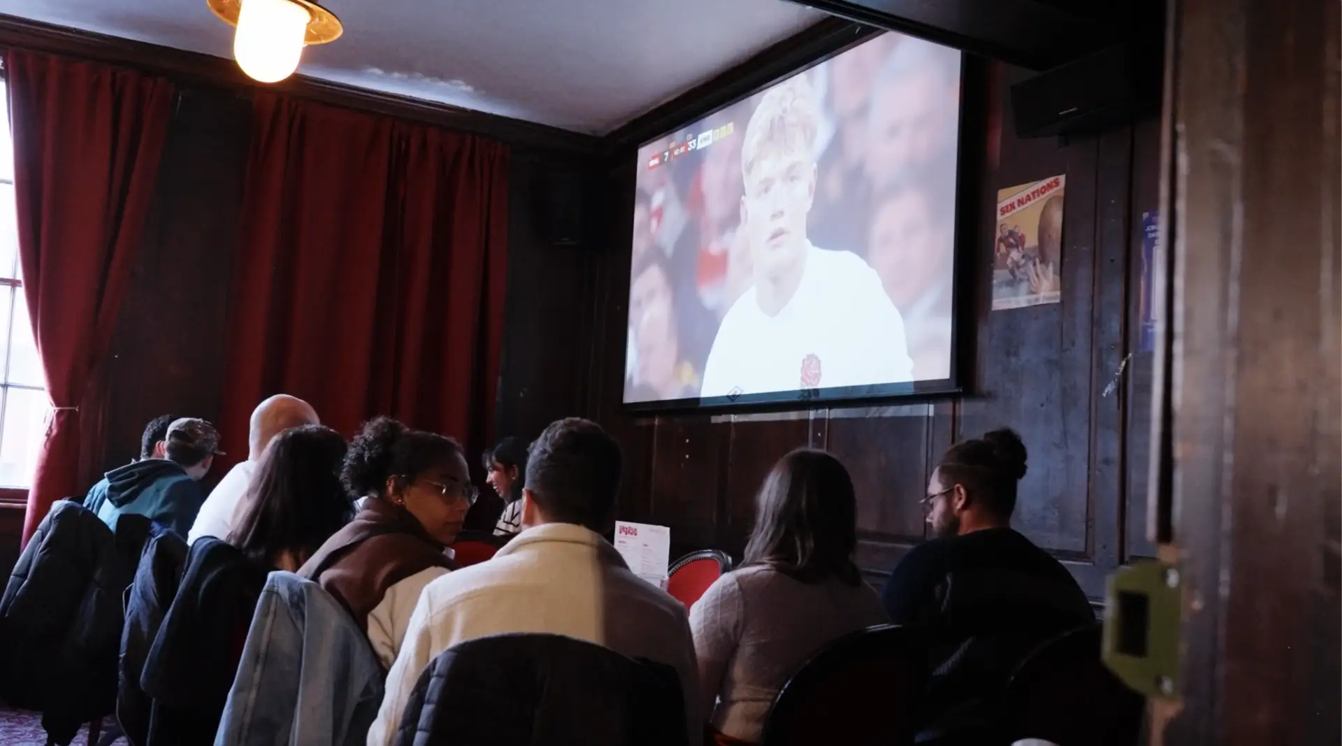sports fans watching a live game on a large projector screen in central Bristol pub on Old Market Road. 