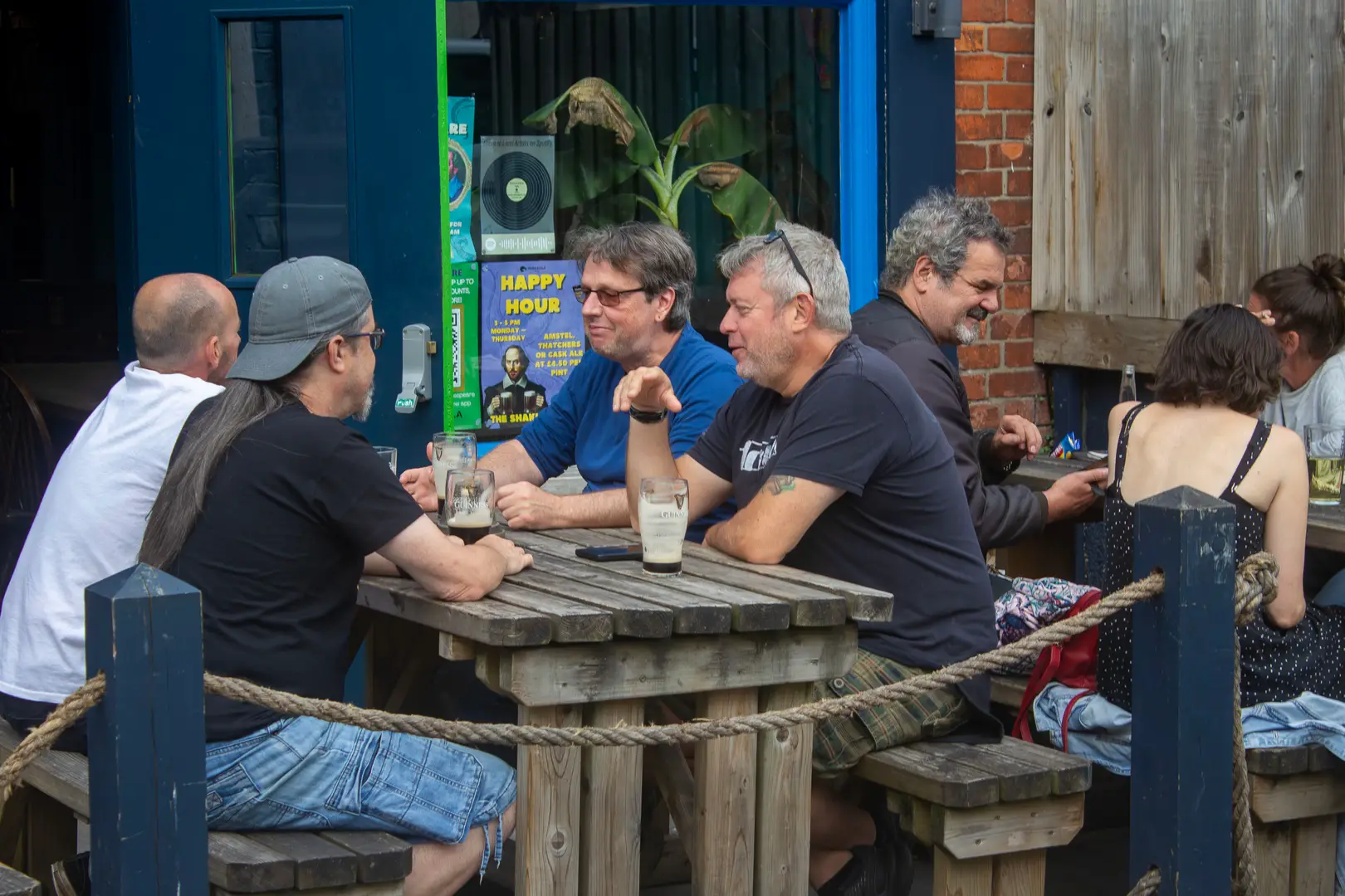 friends and family customers sat outside on a pub bench, laughing at The Shakespeare, Totterdown, Bristol