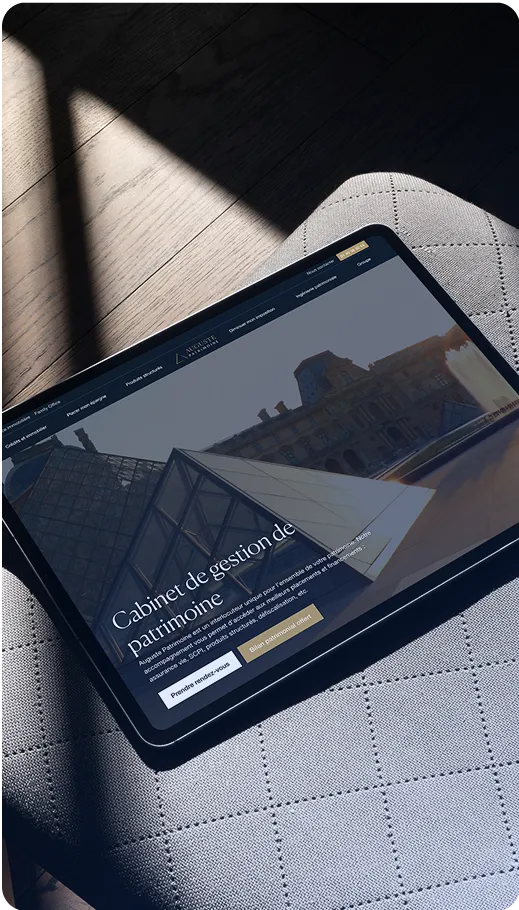 Tablette posée sur une chaise, affichant un site internet de conseils ou services en gestion de patrimoine immobilier, avec une photo de toits parisiens.