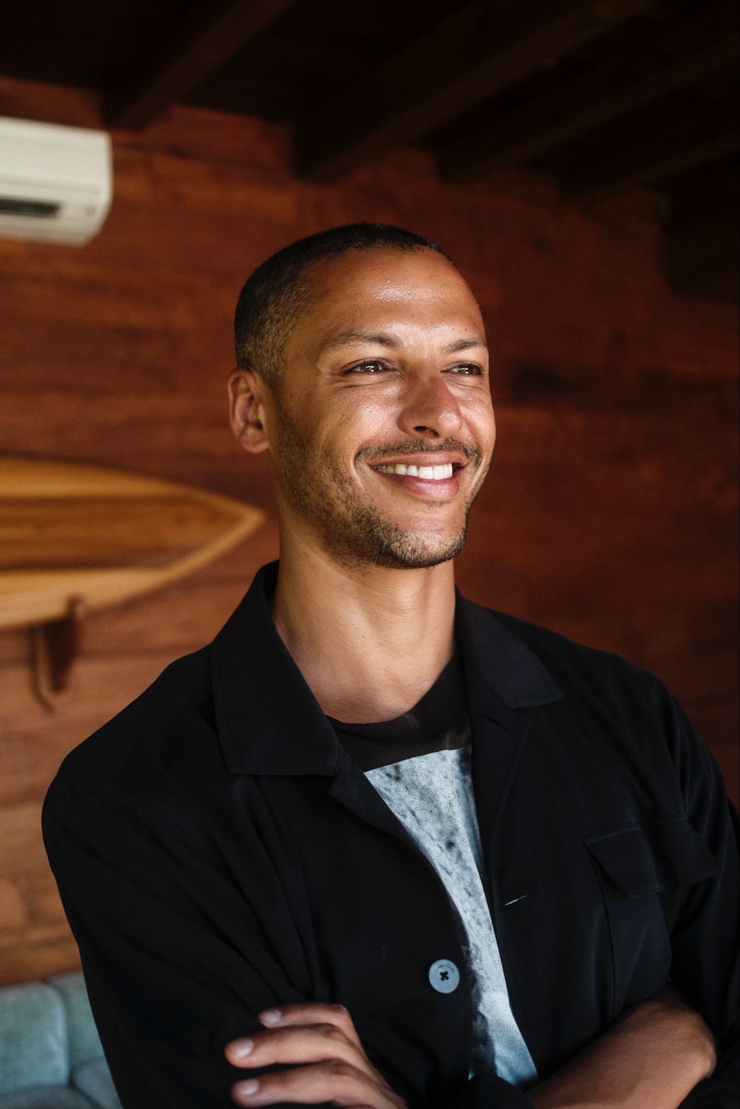 Simo Azzaoui steht mit verschränkten Armen vor einer hölzernen Wand.