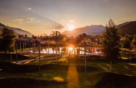 Die Kristallwolke in den Swarovski Kristallwelten bei Sonnenuntergang – funkelnde Wolken aus Kristall spiegeln sich im schwarzem Spiegelwasser, umgeben von sanfter Berglandschaft.