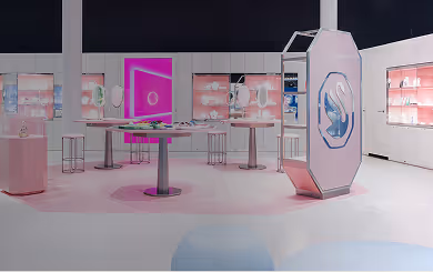 Innenansicht des Swarovski Kristallwelten Stores in Wattens: moderne Verkaufsfläche mit weißen Möbeln, rosa Akzenten, leuchtenden Präsentationsinseln und Vitrinen voller Schmuckstücke.