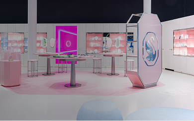 Interior view of the Swarovski Kristallwelten Store Wattens: modern retail space with white furniture, pink accents, glowing presentation islands and display cases full of jewelry.