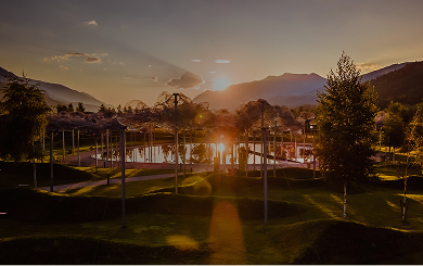 Die Kristallwolke in den Swarovski Kristallwelten bei Sonnenuntergang – funkelnde Wolken aus Kristall spiegeln sich im schwarzem Spiegelwasser, umgeben von sanfter Berglandschaft.