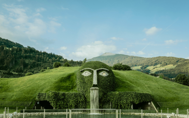 Der markante Riese mit leuchtenden Augen und Wasserfall ist das Herzstück der Swarovski Kristallwelten Wattens, umgeben von der Tiroler Bergkulisse.