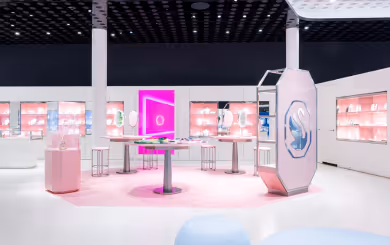 Innenansicht des Swarovski Kristallwelten Stores in Wattens: moderne Verkaufsfläche mit weißen Möbeln, rosa Akzenten, leuchtenden Präsentationsinseln und Vitrinen voller Schmuckstücke.