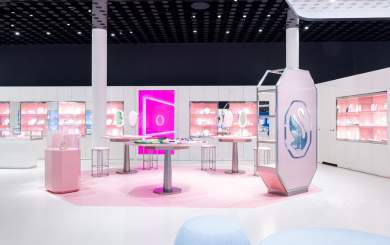 Interior view of the Swarovski Kristallwelten Store Wattens: modern retail space with white furniture, pink accents, glowing presentation islands and display cases full of jewelry.