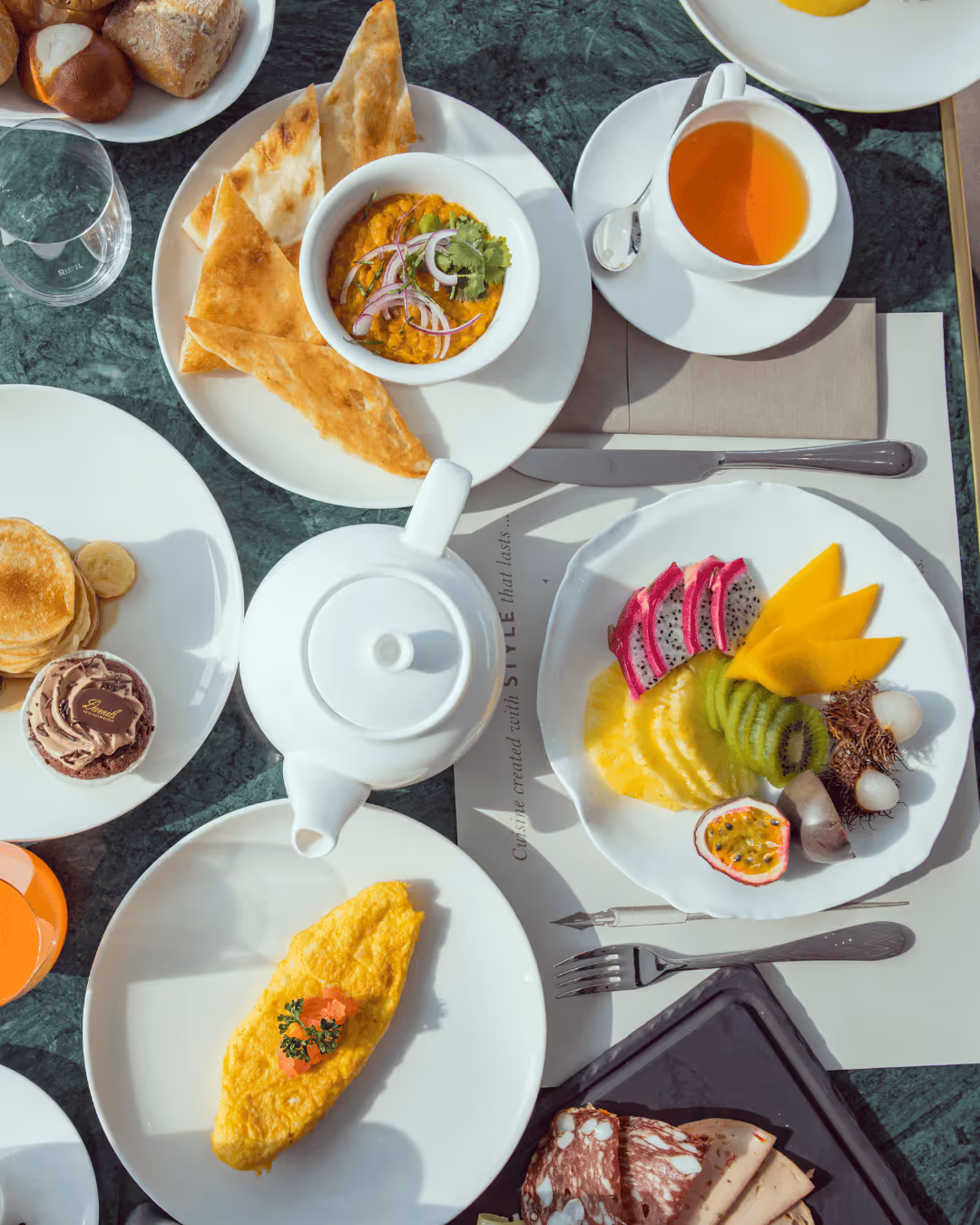 A varied breakfast in the Restaurant Daniels Kristallwelten by DoN: fresh fruit, omelets, pancakes with ice cream, cereal, bread, tea and juices, served on an elegantly set table.