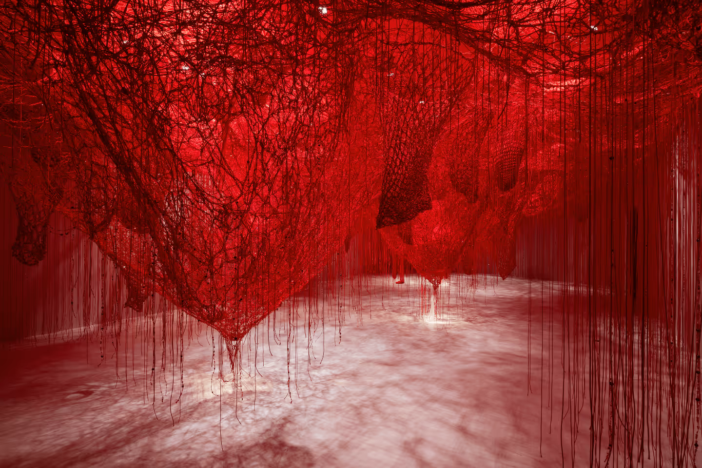 Rauminstallation der Künstlerin Chiharu Shiota in den Swarovski Kristallwelten: dichte Netze aus roten Fäden spannen sich über den gesamten Raum und hängen bis zum Boden herab, wodurch eine eindrucksvolle, begehbare Kunstlandschaft entsteht.