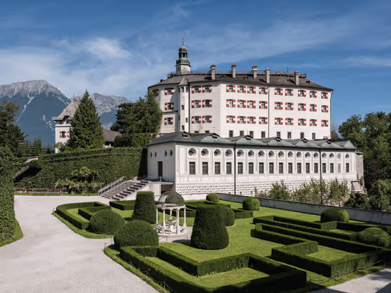 Schloss Ambras bei Innsbruck mit prächtiger Renaissance-Architektur und barocker Gartenanlage, eingebettet in die Tiroler Berglandschaft.