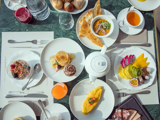A varied breakfast in the Daniels Kristallwelten restaurant: fresh fruit, omelets, pancakes with ice cream, cereal, bread, tea and juices, served on an elegantly set table.