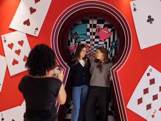 Disney photo spot at Swarovski Kristallwelten Store Wattens — two visitors pose in an Alice in Wonderland scene with oversized playing cards and a key motif.