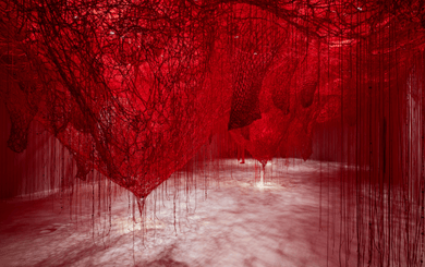 Room installation by artist Chiharu Shiota at Swarovski Kristallwelten: dense networks of red threads span the entire room and hang down to the floor, creating an impressive, walk-in art landscape.