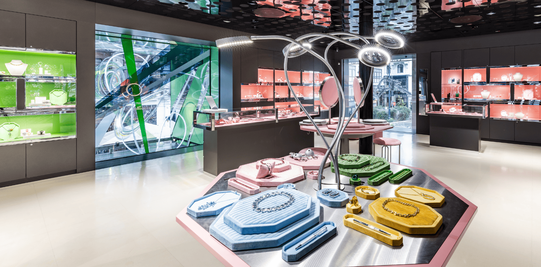 Innenansicht des Swarovski Kristallwelten Stores in Wien mit farbenfrohen Vitrinen und modernen Schmuckpräsentationen in pastellfarbenen Auslagen.